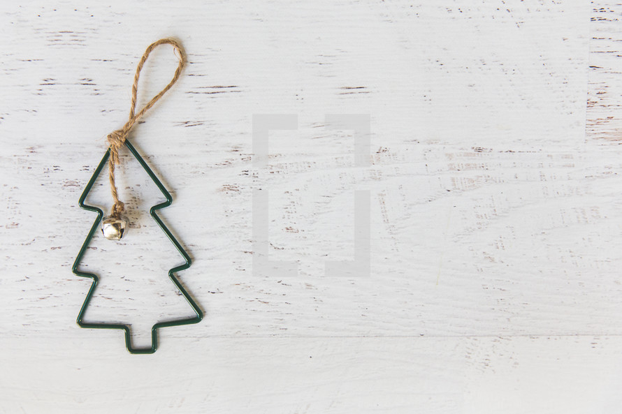 Green Christmas tree ornament on a white wood background 
