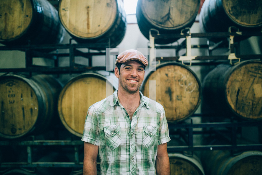 man in a winery with barrels in the background 
