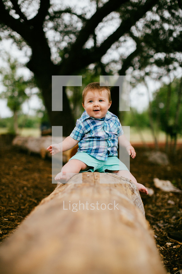 infant son sitting on a log 