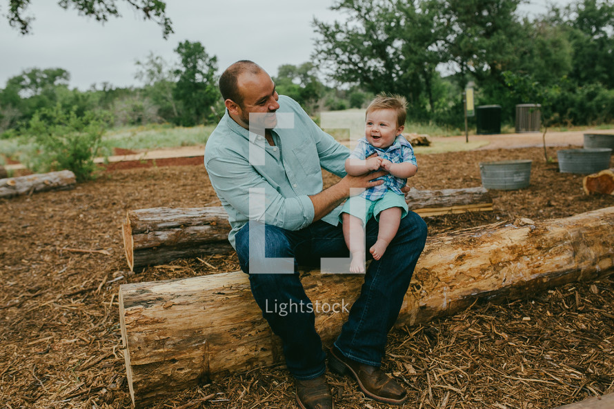 father and infant son on a log 