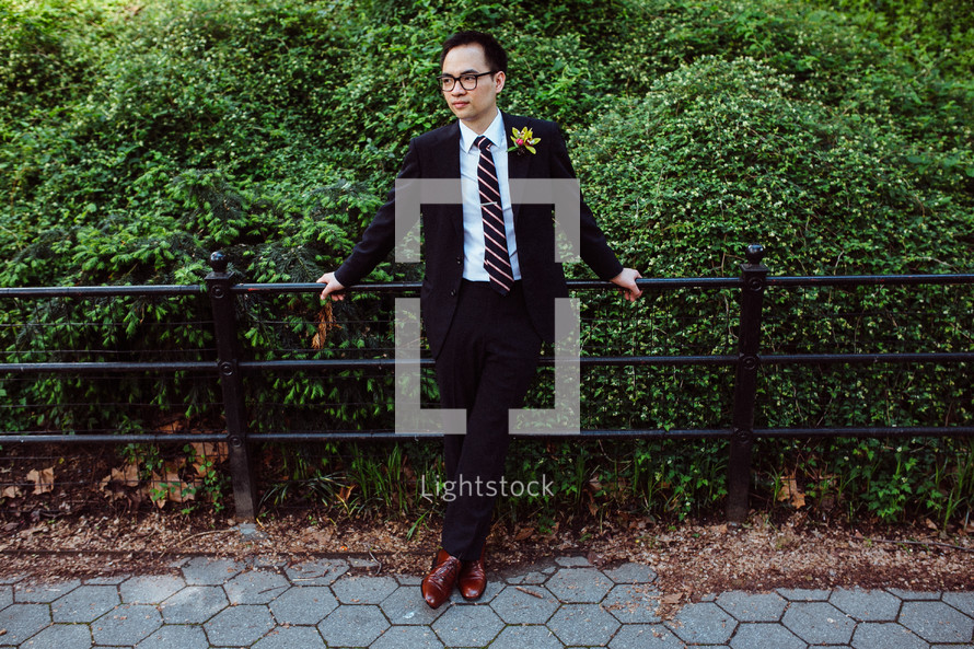 man in a suit leaning against a railing 