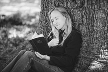 woman sitting under a tree reading a Bible