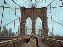 man giving a peace sign on the Brooklyn Bridge 
