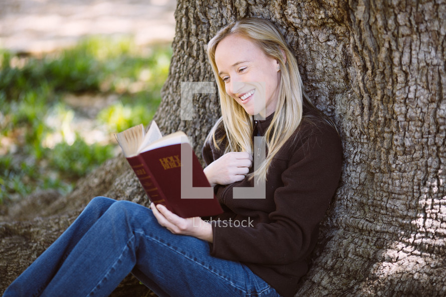 woman reading a Bible under a tree