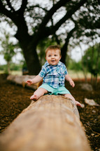 infant son sitting on a log 