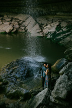 couple standing under a waterfall 