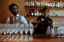 Bartenders pouring champagne at a bar.