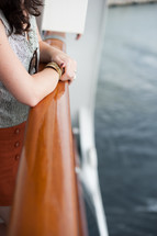 woman at a railing on a boat looking out at the water 