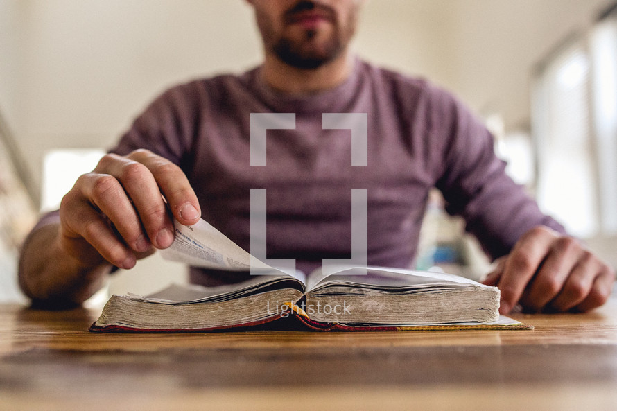 man reading a Bible and turning pages 