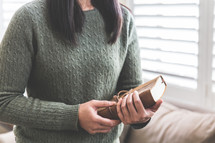a woman in a sweater holding a Bible 