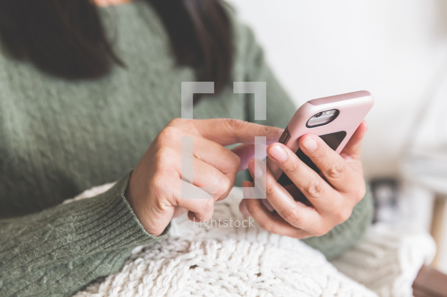 a woman texting snuggled up in a blanket 