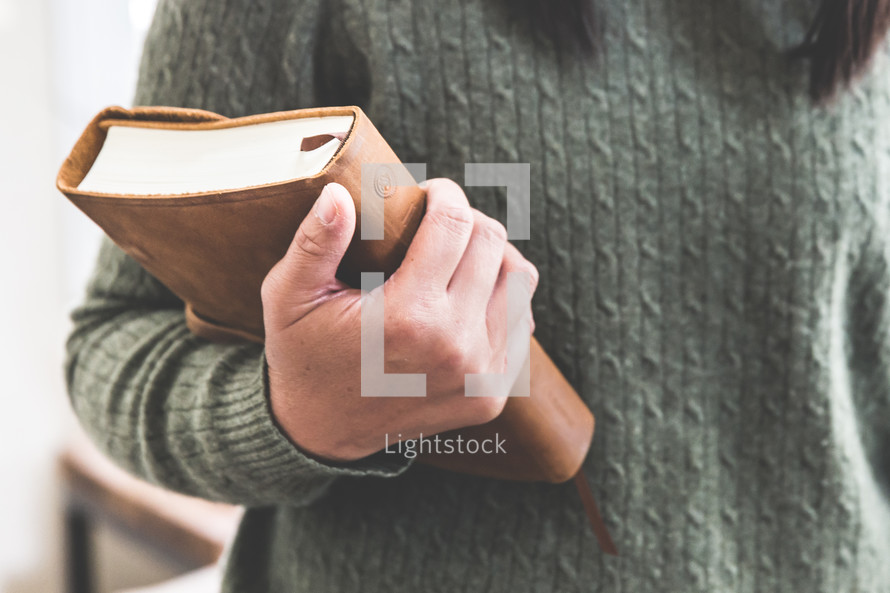 a woman in a sweater holding a Bible