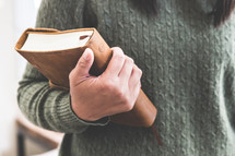 a woman in a sweater holding a Bible