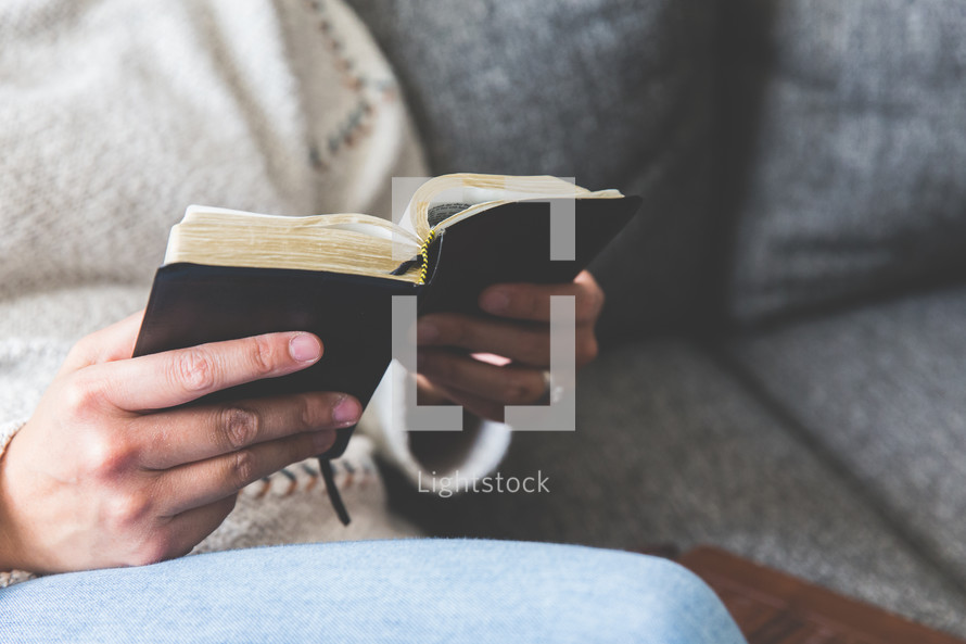 a woman sitting on a couch reading a Bible 