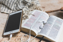 open Bible with cellphone, earbuds, and scarf 