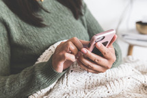 a woman snuggled up in a blanket texting 