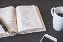 pen on an open Bible and coffee mug