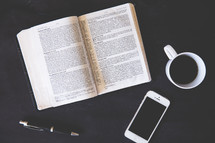 open Bible, pen, iPhone, coffee mug 