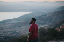 a man standing on a mountaintop looking out at the view