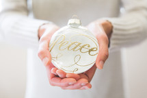 a woman holding an ornament with the word peace on it 
