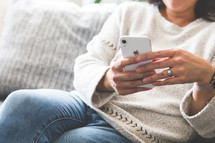 a woman sitting on a couch looking at a cellphone screen 