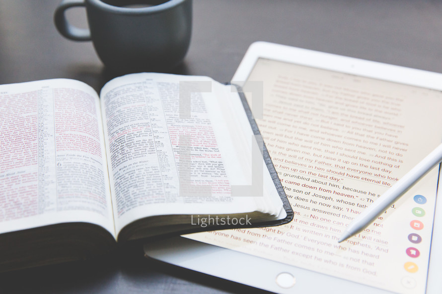 An open Bible, electronic tablet, and a cup of coffee.