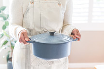 a woman holding a blue dutch oven 