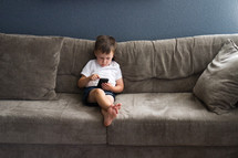 boy child with a cellphone on a couch 