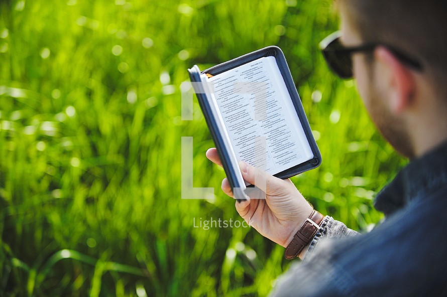 a man reading a Bible in the grass 