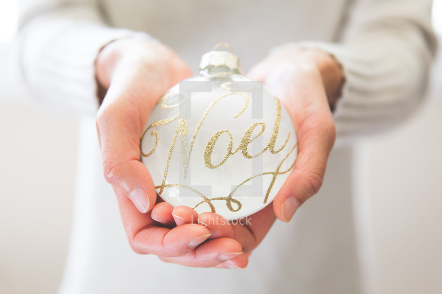 a woman holding an ornament with the word noel on it 