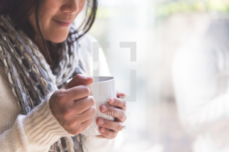 a woman holding a warm mug 