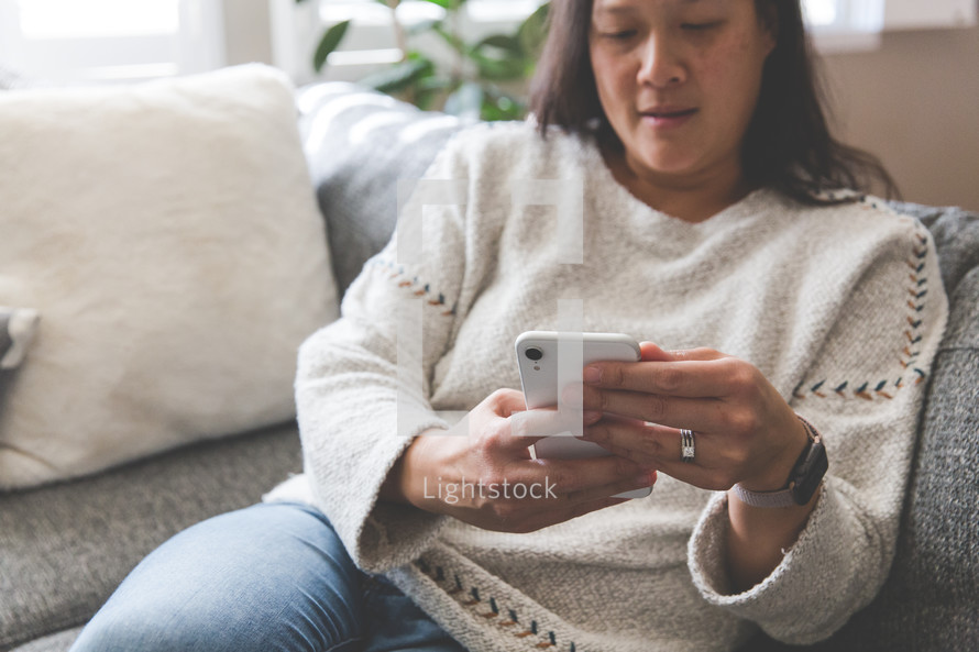 a woman sitting on a couch looking at a cellphone 