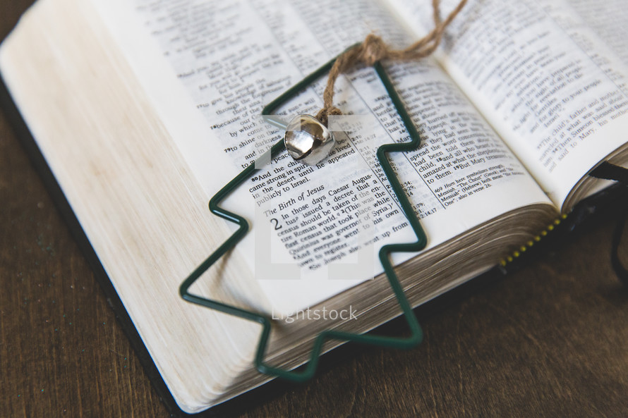 green Christmas tree ornament on the pages of a Bible 