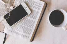 iphone, earbuds, on the pages of an open Bible 