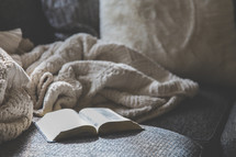 blanket and open Bible on a couch 