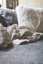 blanket, reading glasses, and open Bible on a couch 