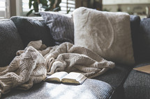 blanket, and open Bible on a couch 