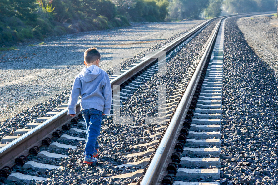 boy child walking alone on railroad tracks 