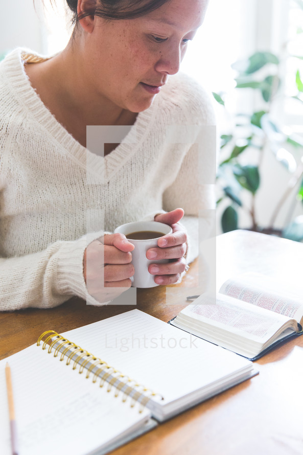 a woman reading a Bible and writing in a journal 
