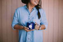 a woman standing holding a coffee mug