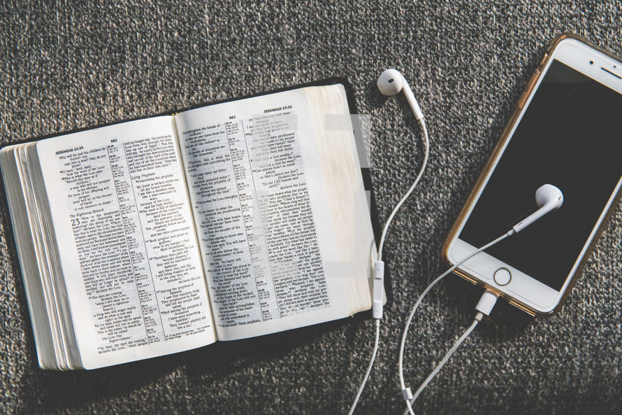 open Bible, earbuds, and cellphone on a couch 