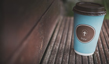 coffee cup with cross on wood ledge 