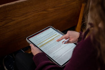 Woman taking notes in her Bible on a tablet
