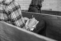 Man taking notes from a sermon in a pew