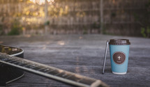 coffee cup with cross, cellphone, and guitar on wood table