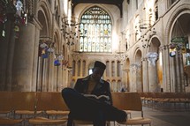 man reading a Bible in an empty church 