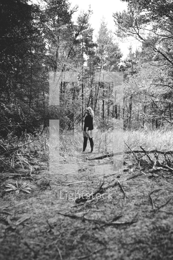 woman standing alone in the woods 