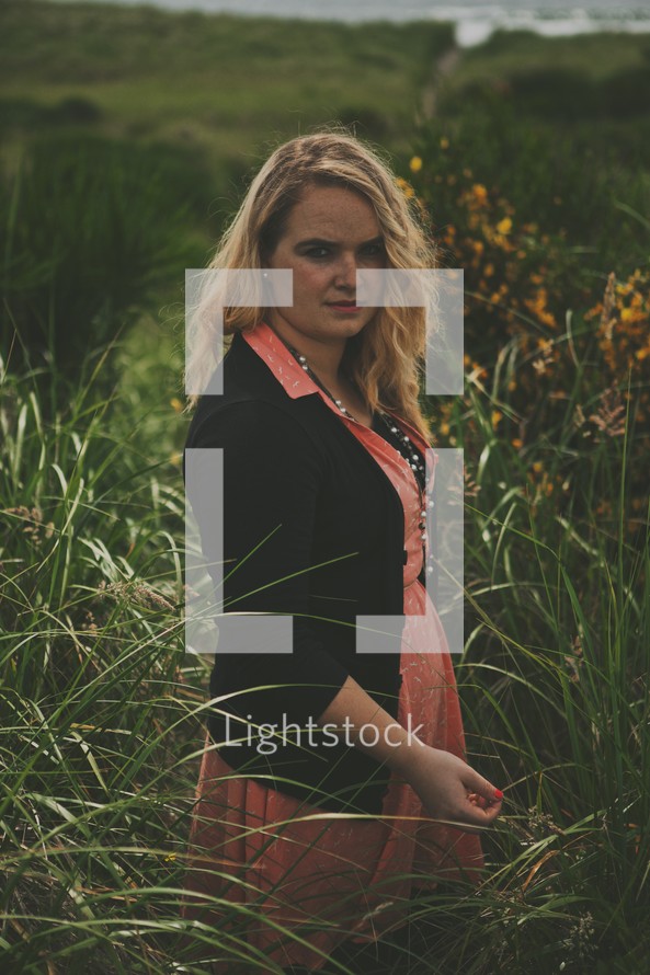 stoic woman standing alone in tall brush 