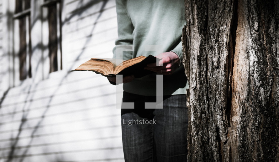 a woman in boots standing on steps in front of a church reading a Bible 
