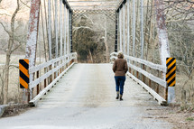 a woman crossing a bridge in winter 